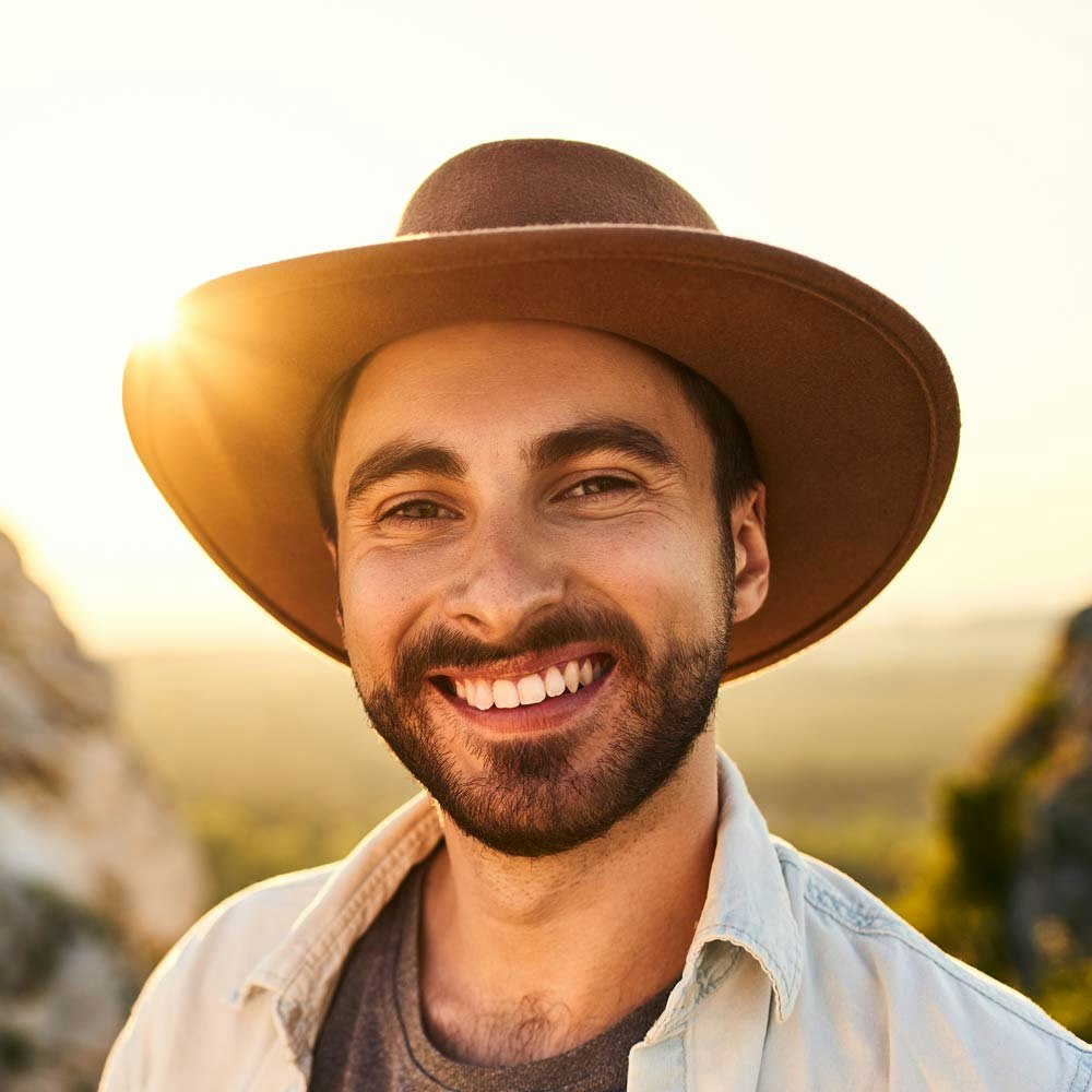 Smiling man after Visian ICL treatment wearing hat in nature