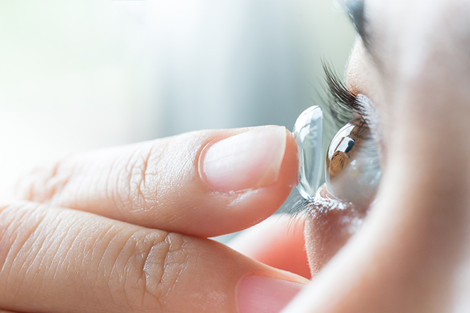 Woman placing contact for keratoconus in her eye
