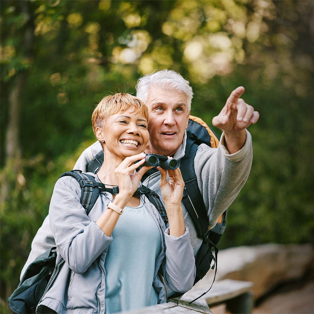 Couple holding binoculars smiling at each other