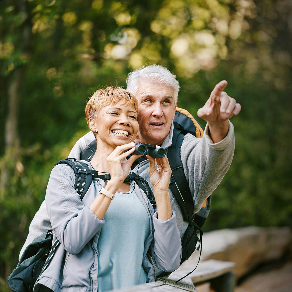 Couple holding binoculars smiling at each other