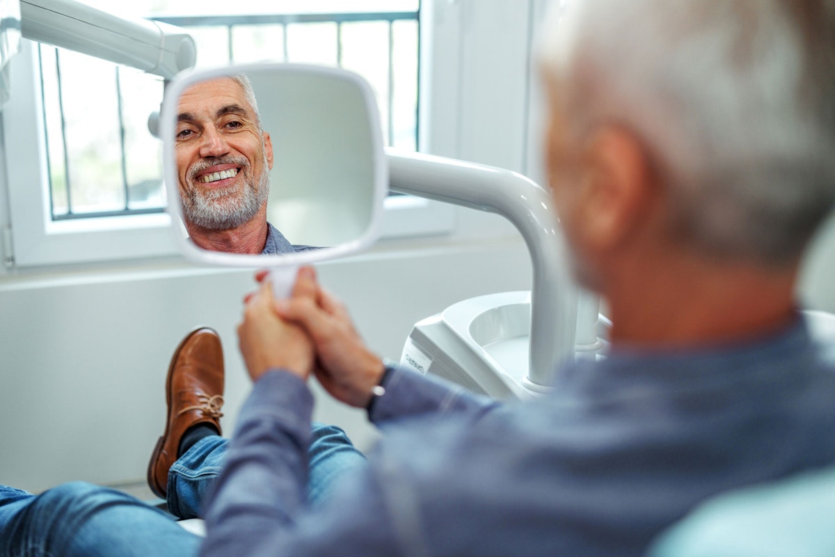 Smiling man looking in a hand mirror