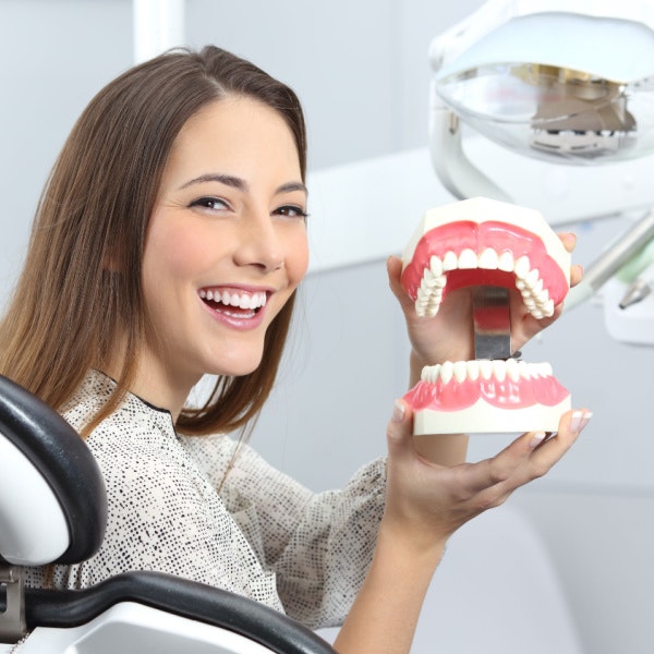 smiling woman holding a model of teeth
