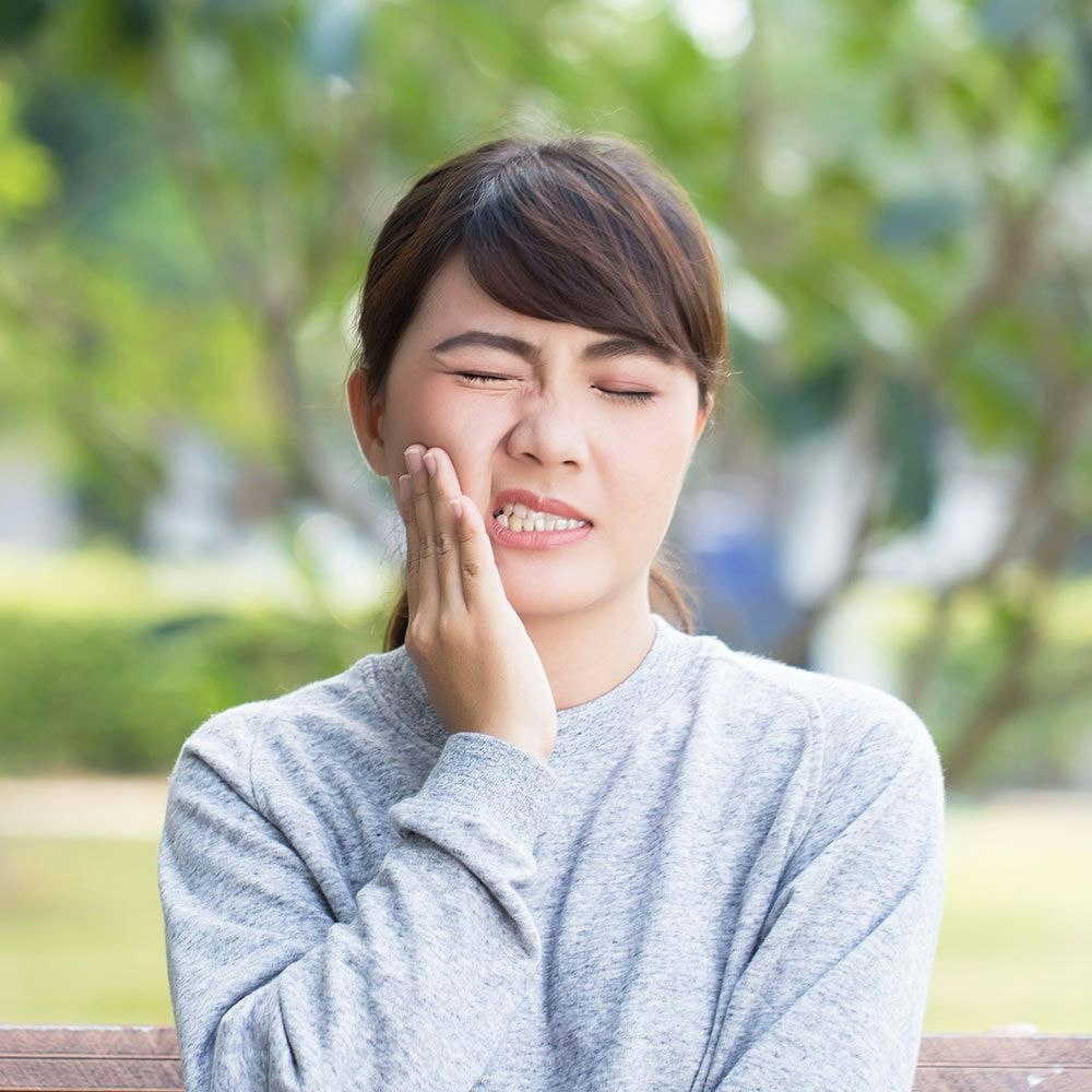 Young woman holding hand to jaw in pain