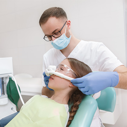 Dentist placing a nitrous oxide mask over the patient's nose