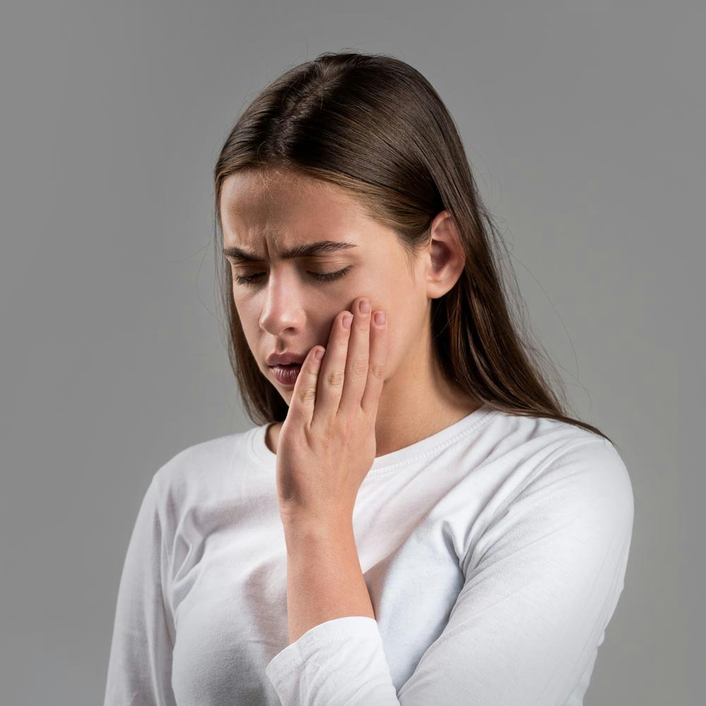 Young girl holding side of mouth in pain