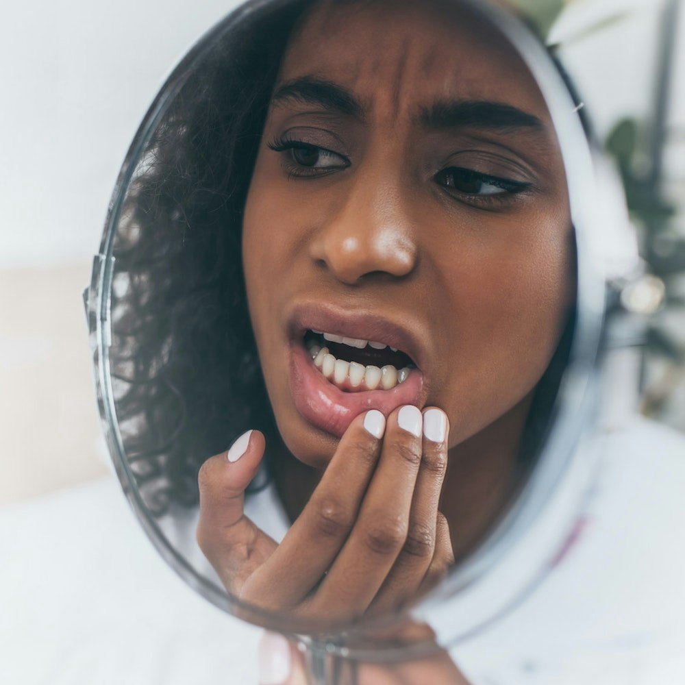 Woman looking at crooked teeth in mirror