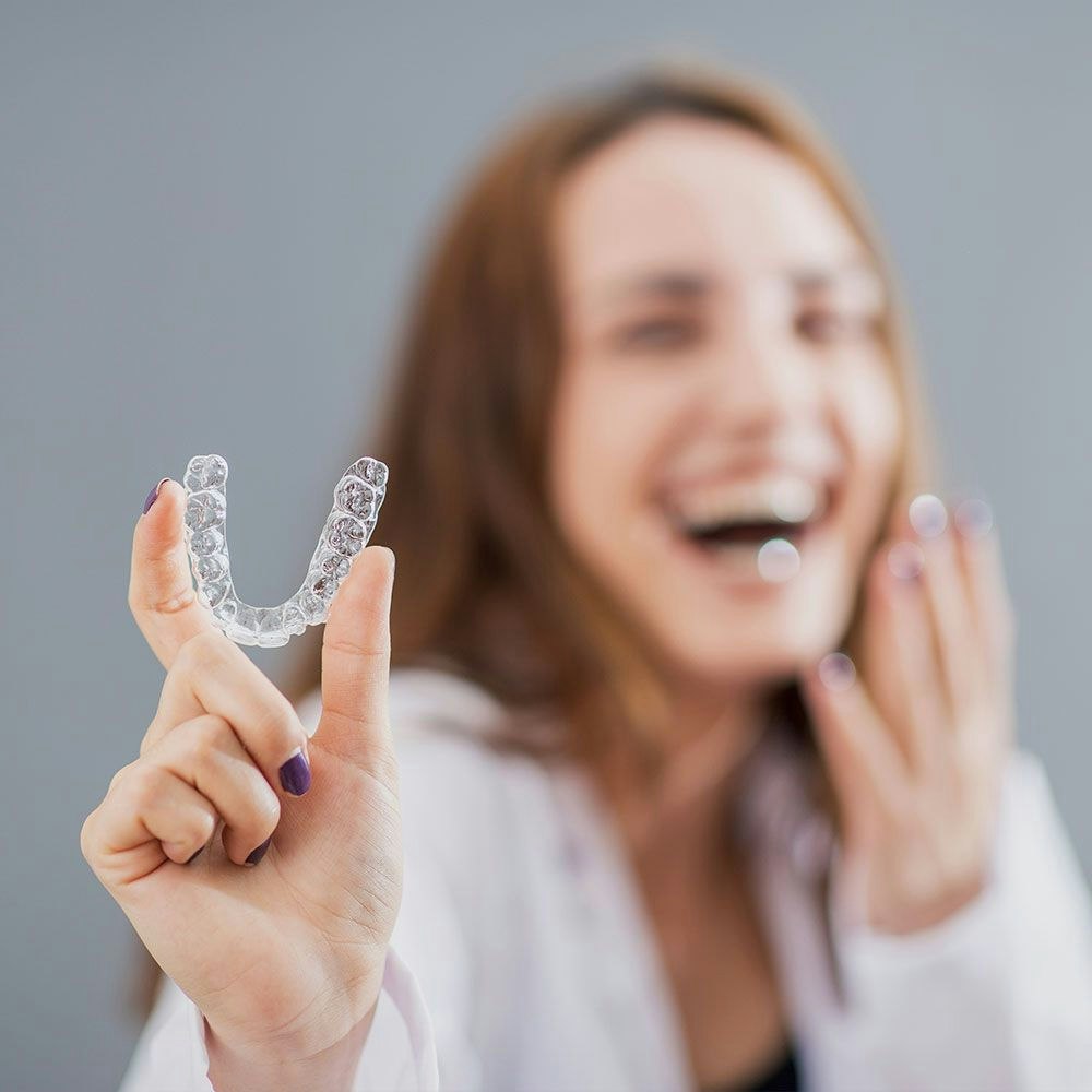 woman holding up Invisalign aligner
