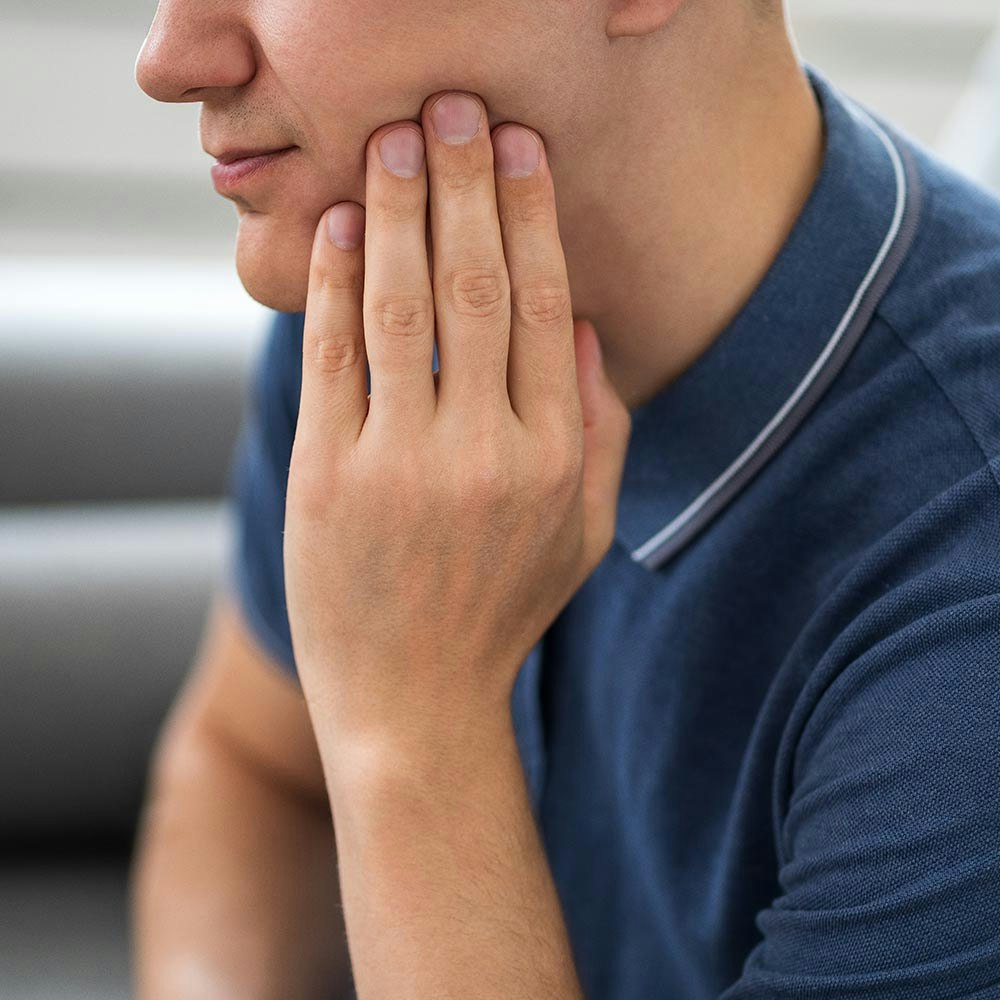 Man holding jaw because of wisdom teeth pain