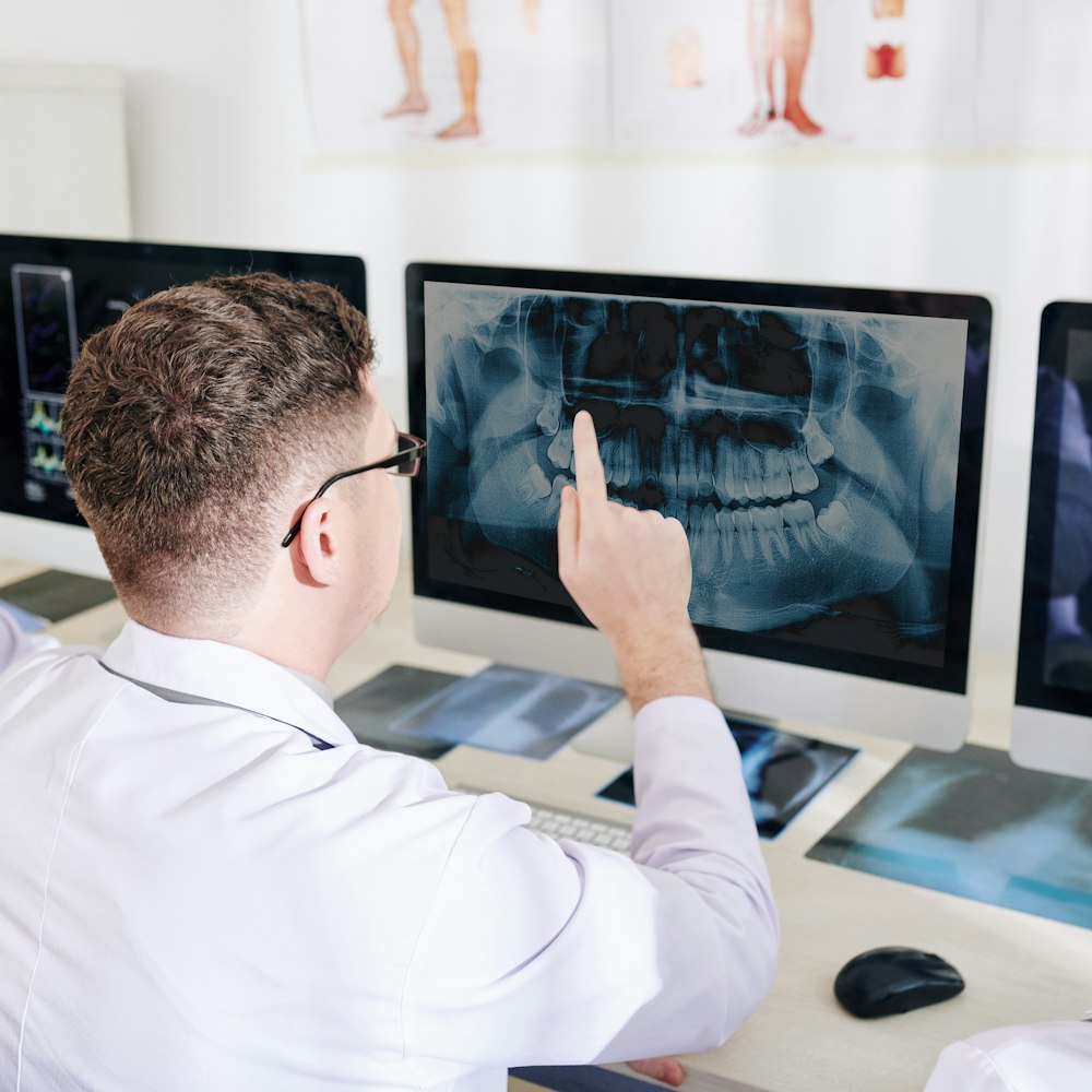 Dentist reviewing panoramic dental X-ray on computer monitor for surgical planning