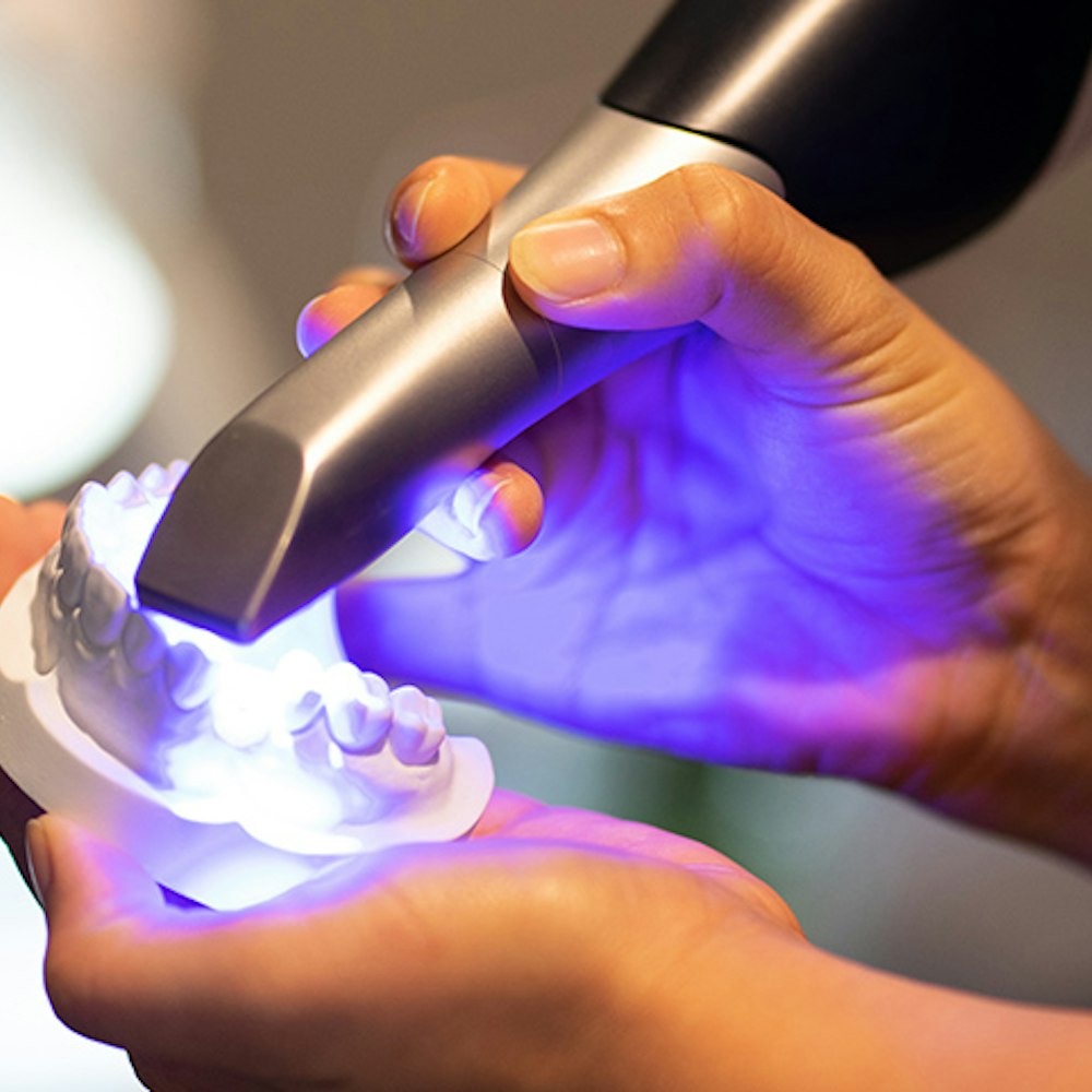 Handheld intraoral scanner capturing digital impression of dental model with blue light
