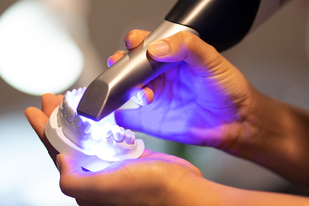 Handheld intraoral scanner capturing digital impression of dental model with blue light
