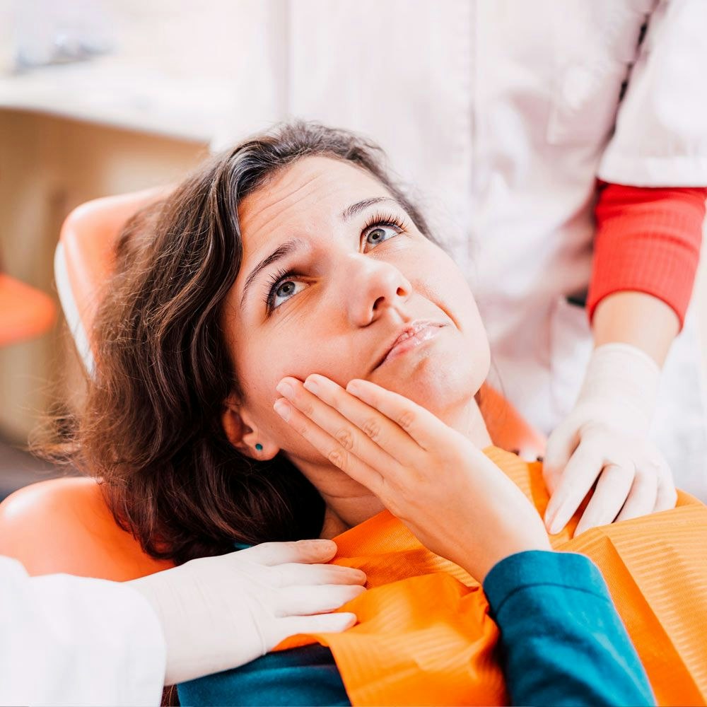 Woman with hand on jaw sitting in dental chair