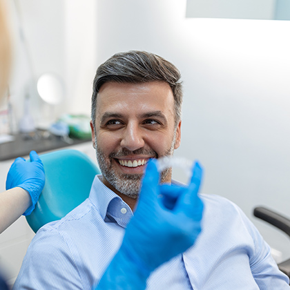 Male patient smiling during a dental consultation, seated in a treatment chair.