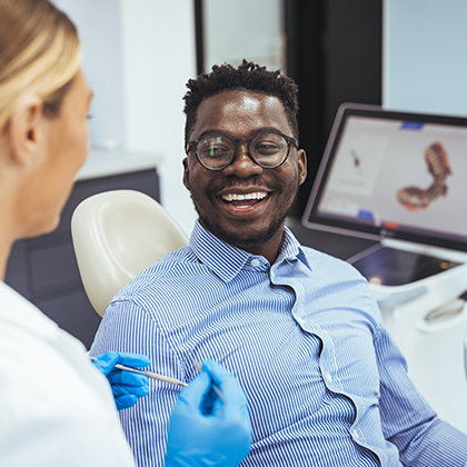 Smiling man talking with a dental professional during a consultation in a modern exam room.
