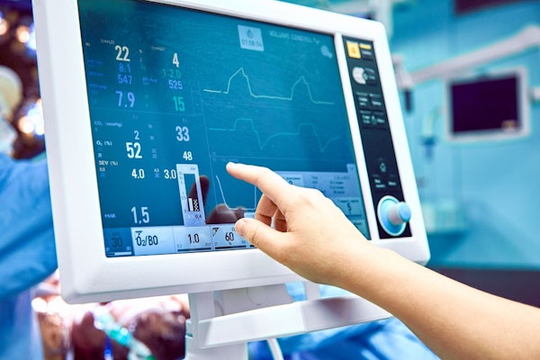 Hand pointing to medical information on monitor