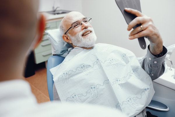 man looking at his dental work in a mirror