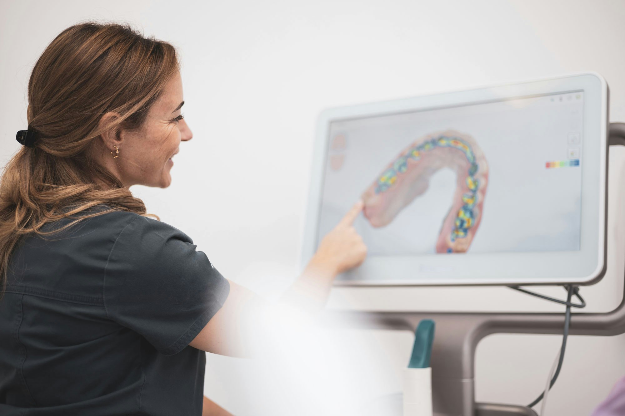 dental professional pointing to teeth on a monitor