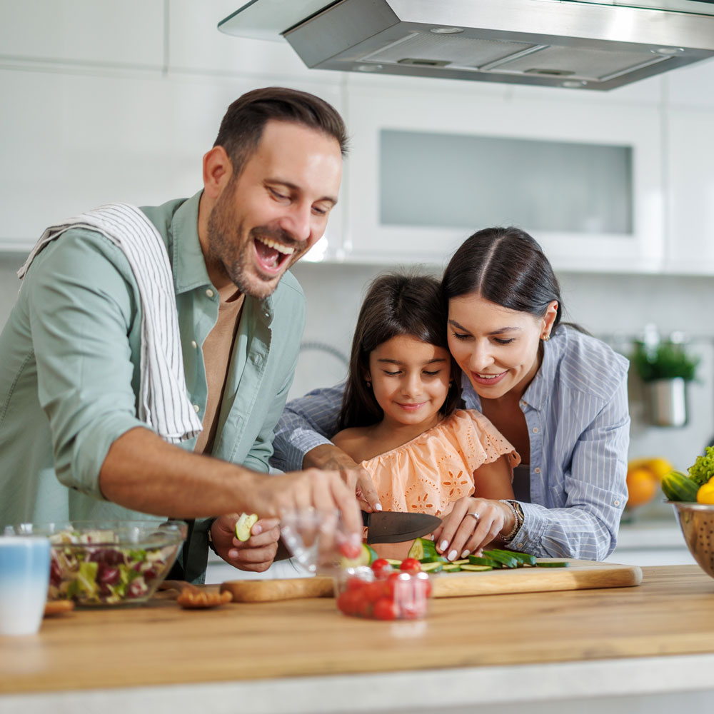 parents and daughter preparing a salad