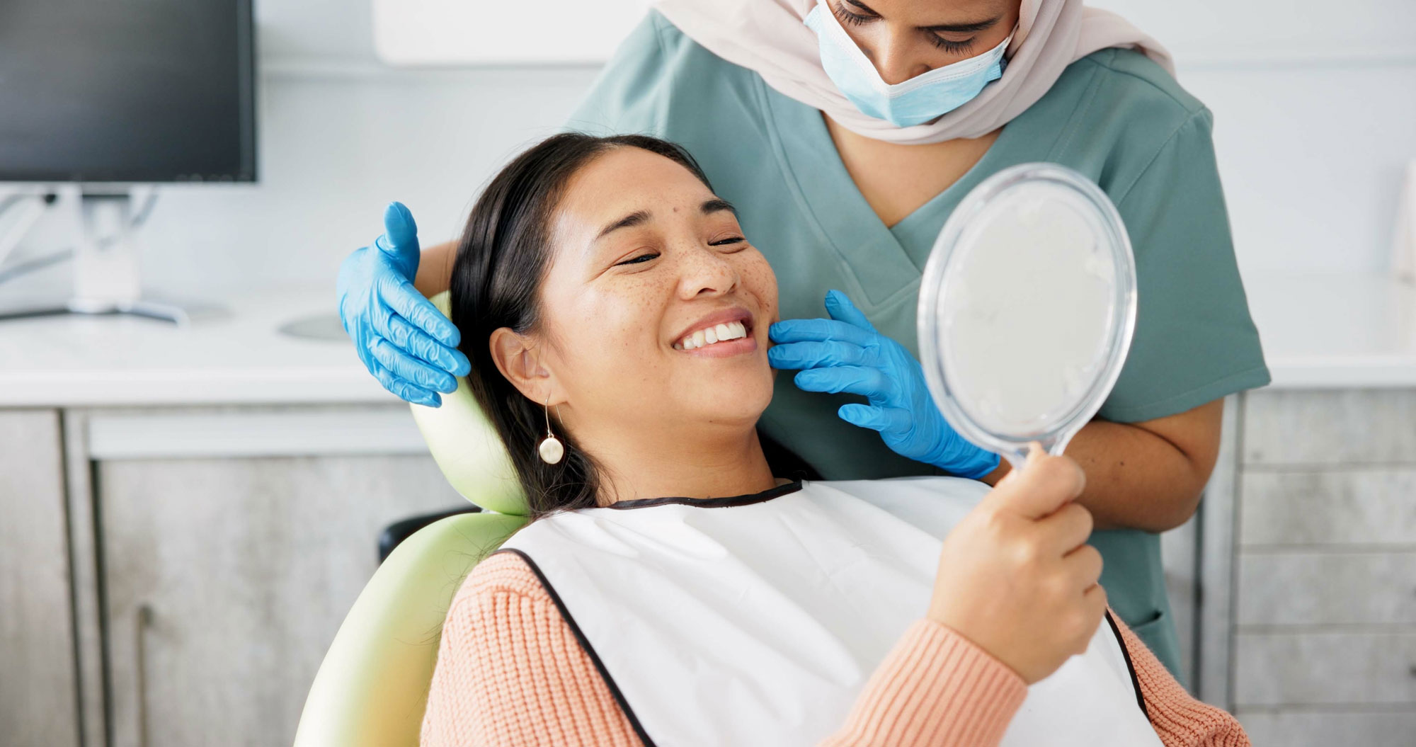 woman smiling in the dental chair with a handheld mirror