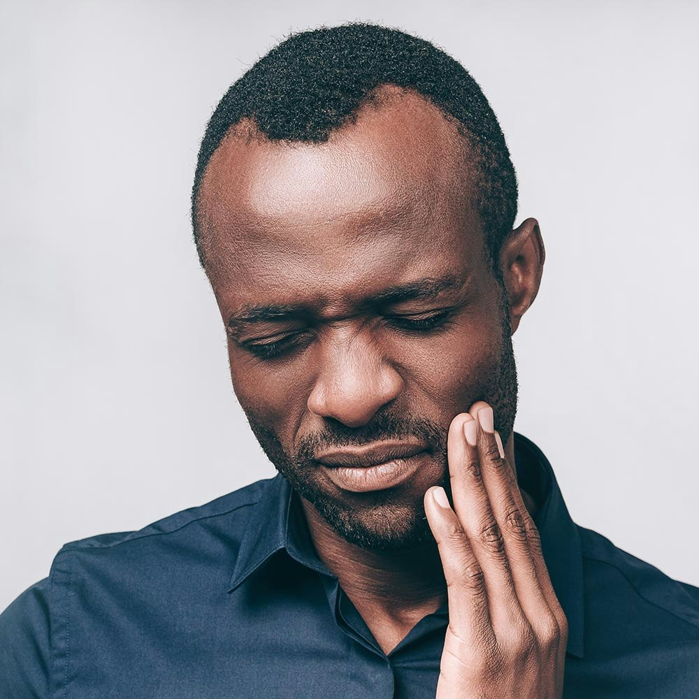 Man holding jaw in pain and in need of oral surgery