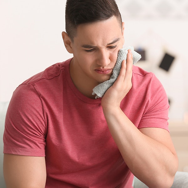 A man applying a cold compress to the mouth