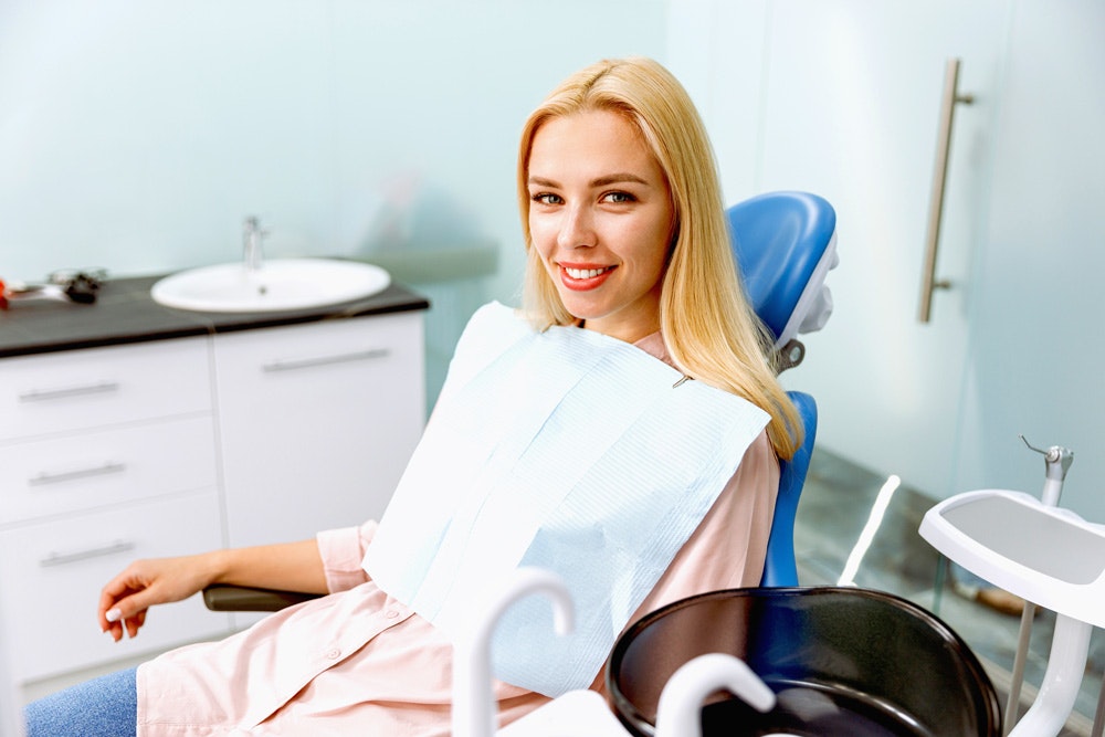 a woman smiles as she calmly waits in the dentists chair
