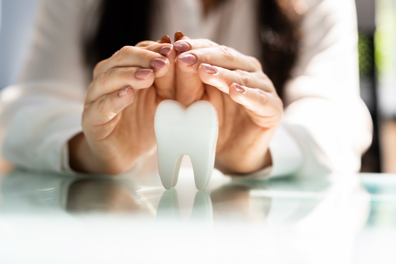 woman covering tooth model with hands