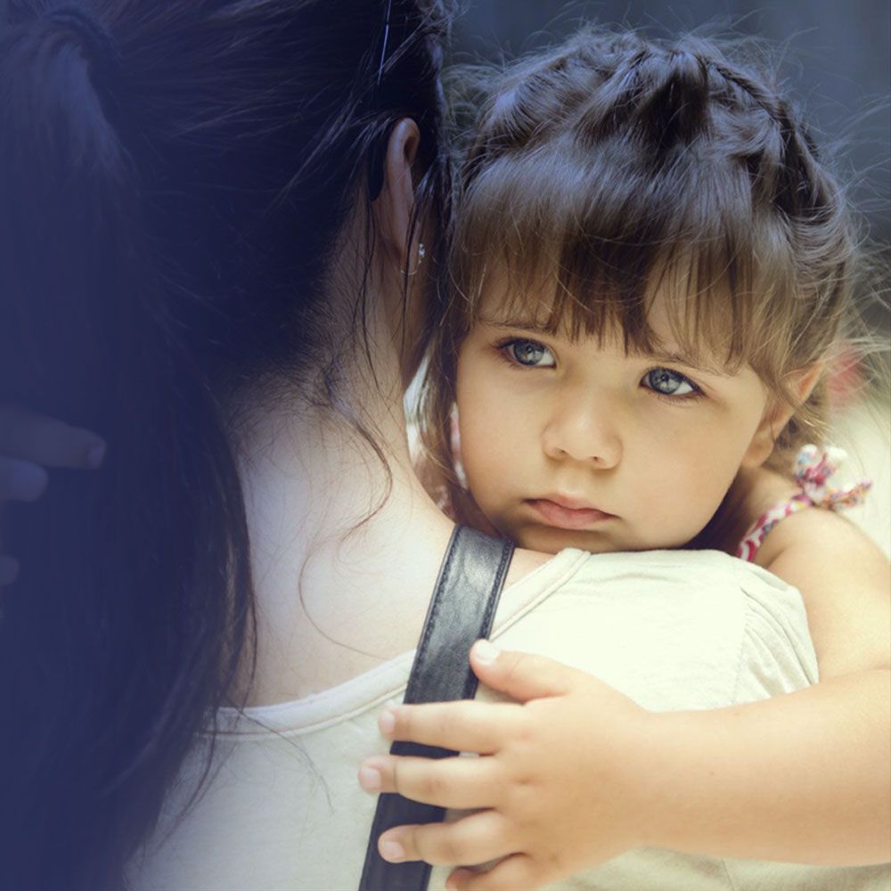 Young girl looking over mom's shoulder