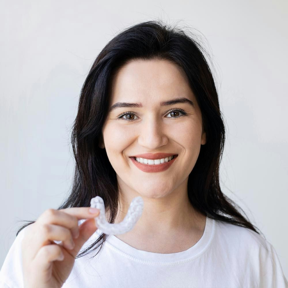 Woman holding an aligner for bruxism