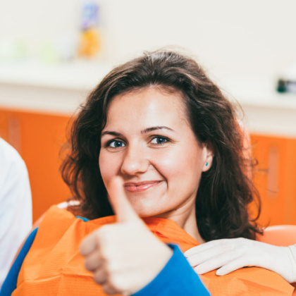 Girl in dental chair giving a thumbs up