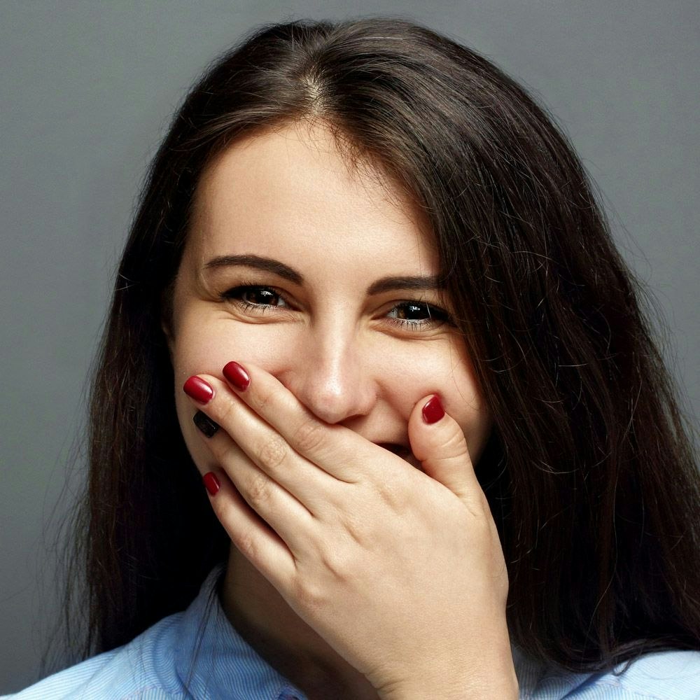 Smiling woman holding hand over mouth