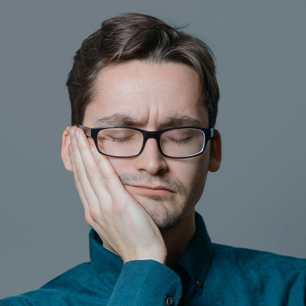 Person holding a side of their face to alleviate gum pain