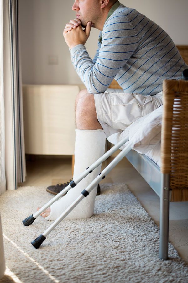 man with crutches staring out window