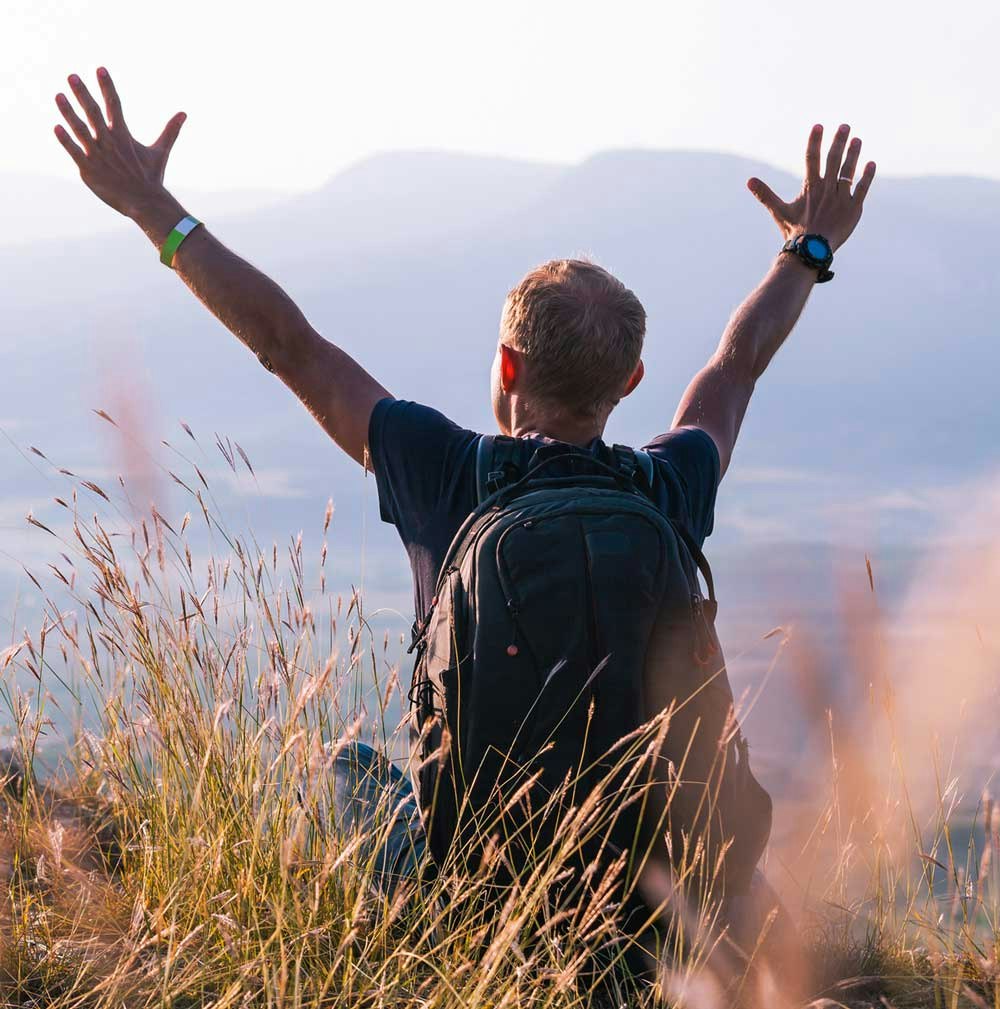 Man raising hands over head in meadow