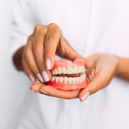 A woman holding a set of dentures