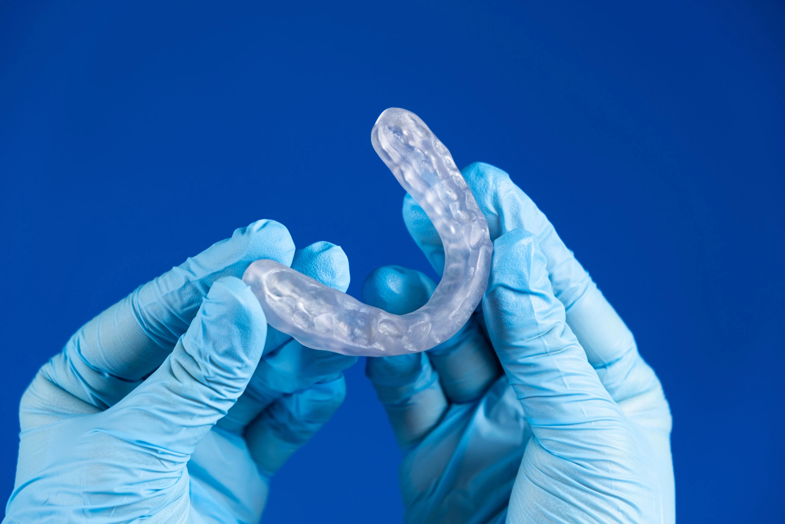 Gloved hands holding a mouth guard