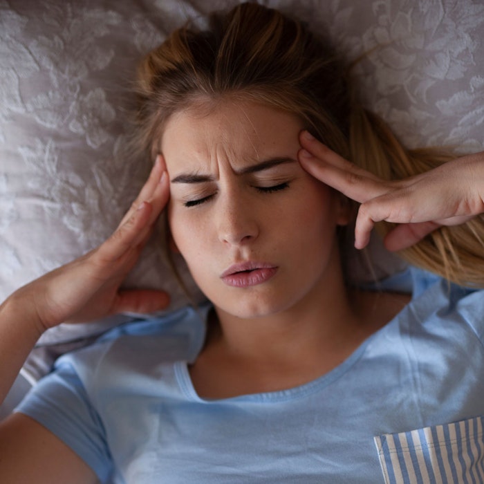 Woman holding her hands to her head in pain