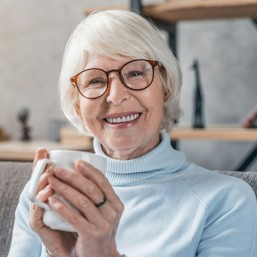 Older woman smiling while holding a cup