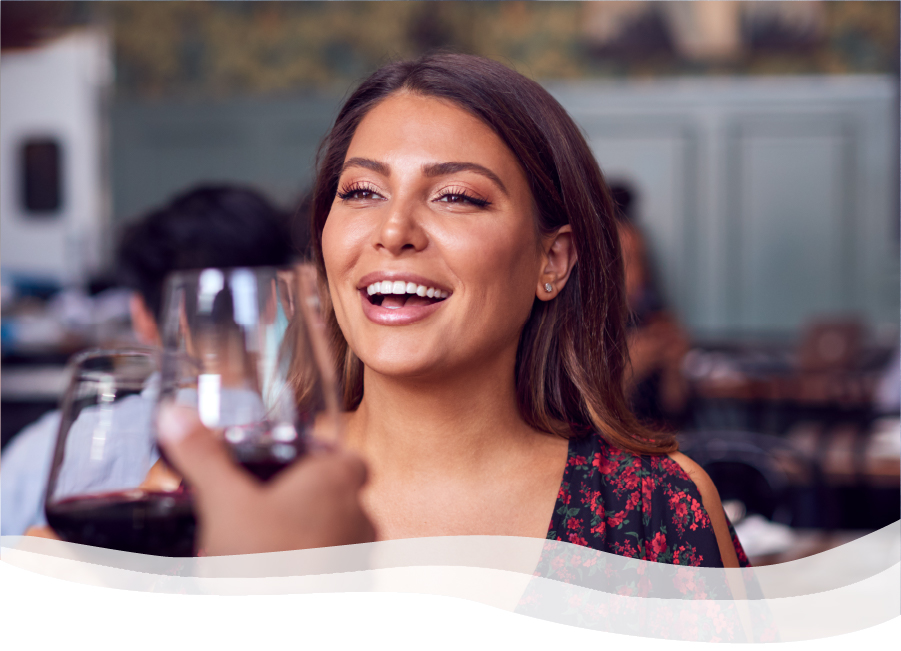 Smiling woman drinking wine with friend