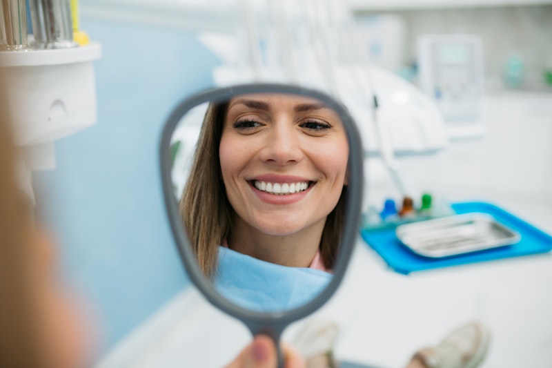 Beautiful woman smiling in the mirror after cosmetic dentistry