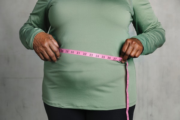 Obese person measuring their waist