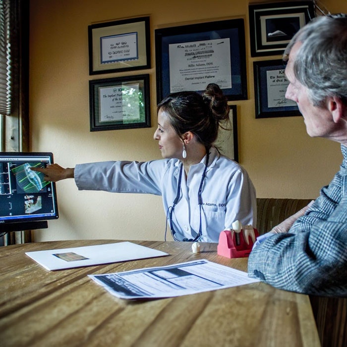 Dr. Adams educating dental patient while pointing to computer monitor
