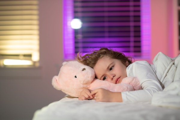 Young girl in bed with a teddy bear