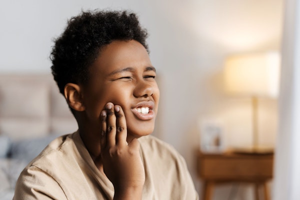 Young boy holding jaw in pain