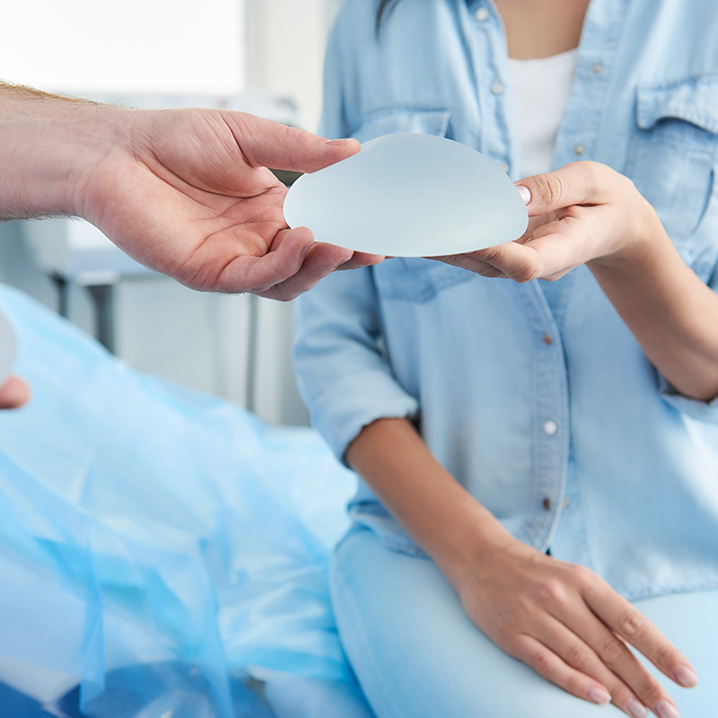 woman holding breast implant during consultation