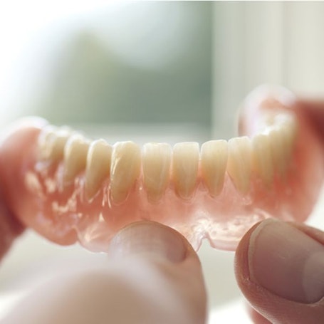 A hand holding lower dentures