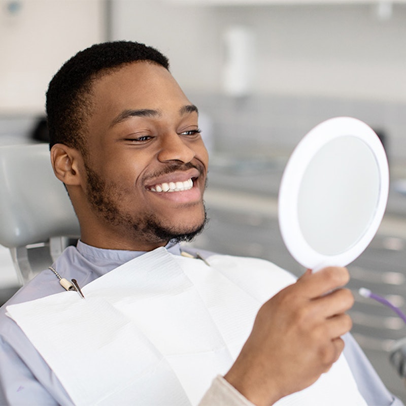 Man smiling into a mirror after dental work