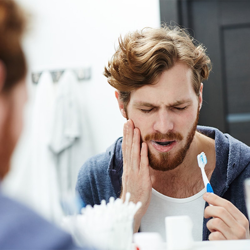 Man brushing his teeth in pain