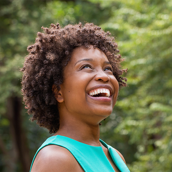 Young woman smiling outside after dental crowns treatment