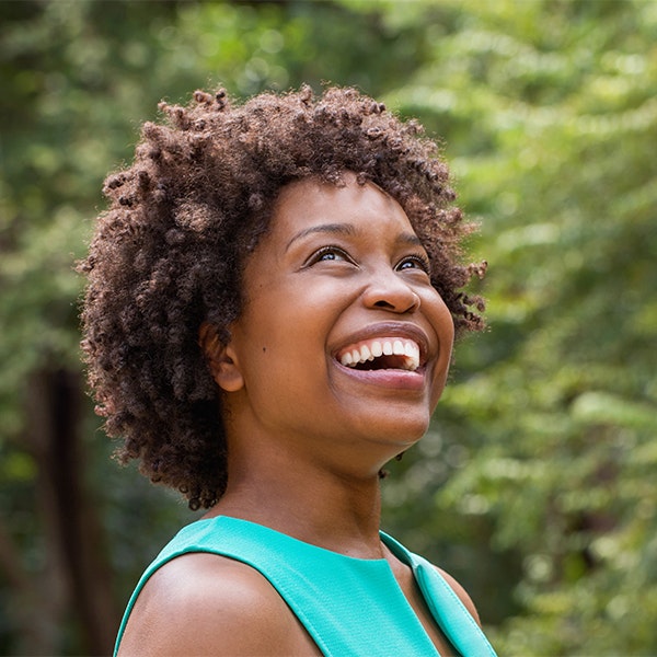 Young woman smiling outside after dental crowns treatment